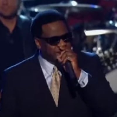 Al Green is on a suit and wearing a spec as he is performing.
